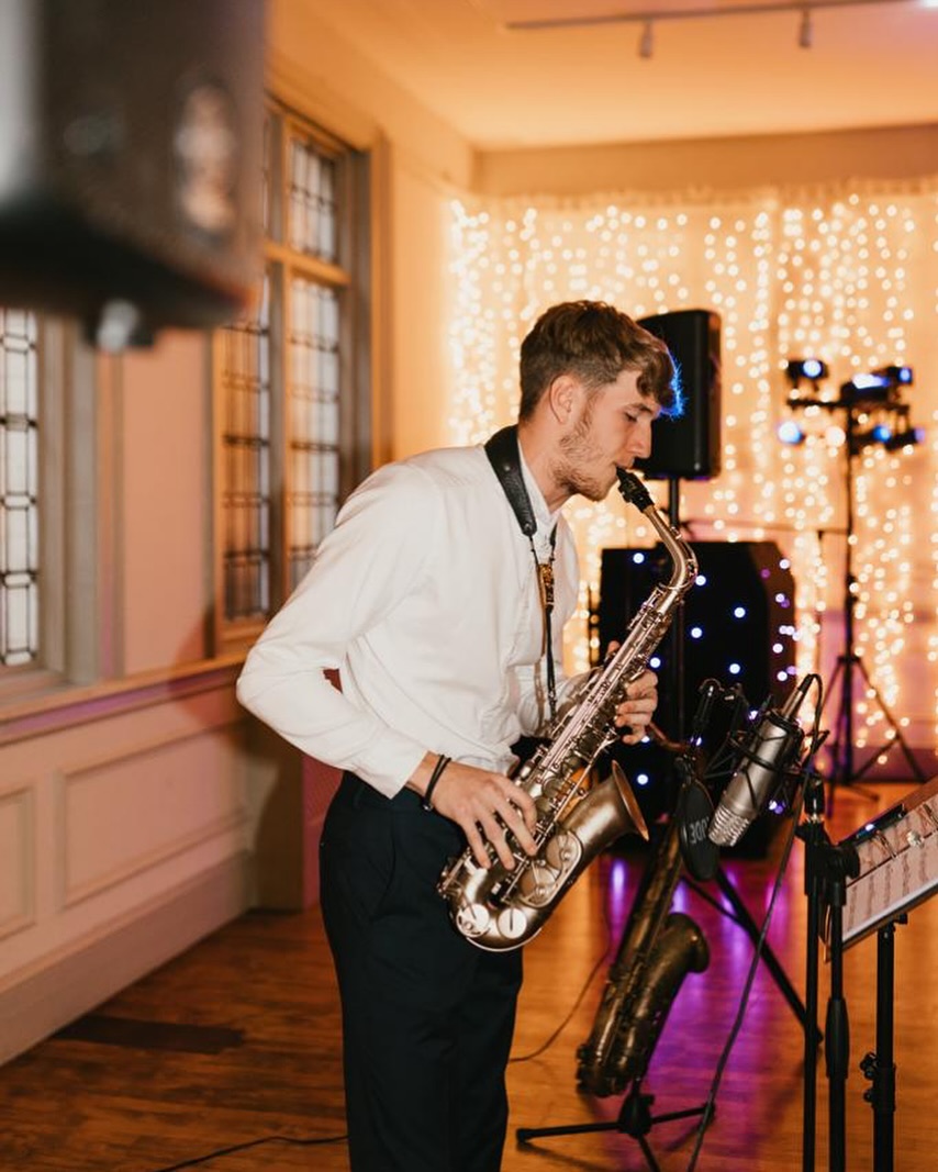 Me playing alto sax at a wedding reception under fairy lights